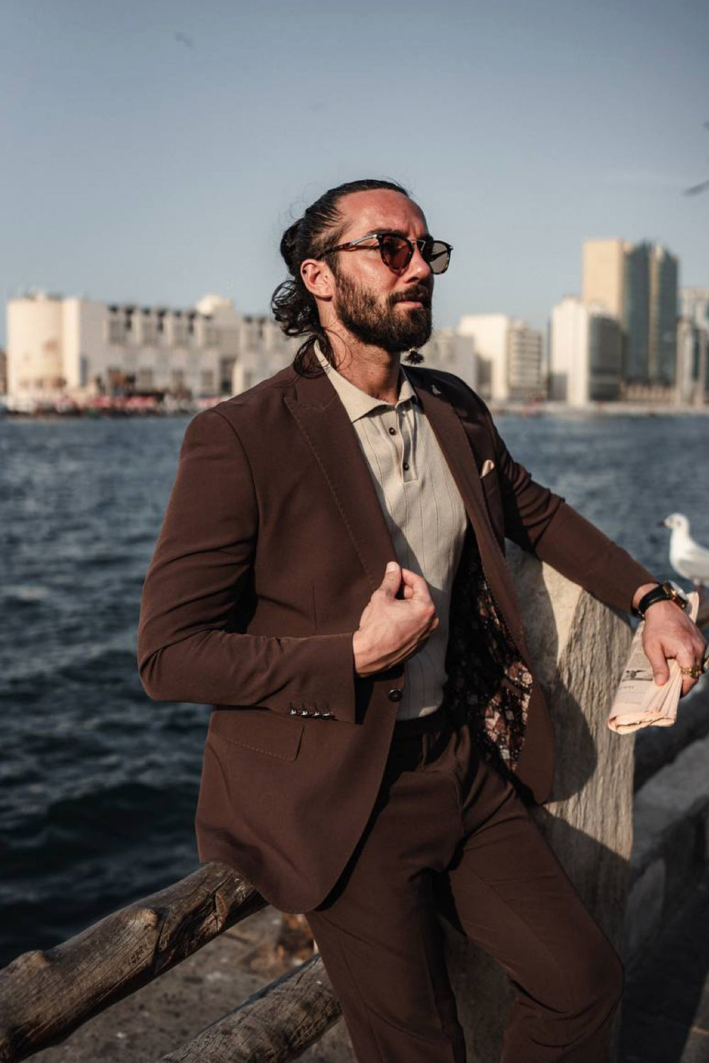 Elegant Mazonni suit in rich brown, worn with light shirt and sunglasses for a polished style suitable for waterfront occasions