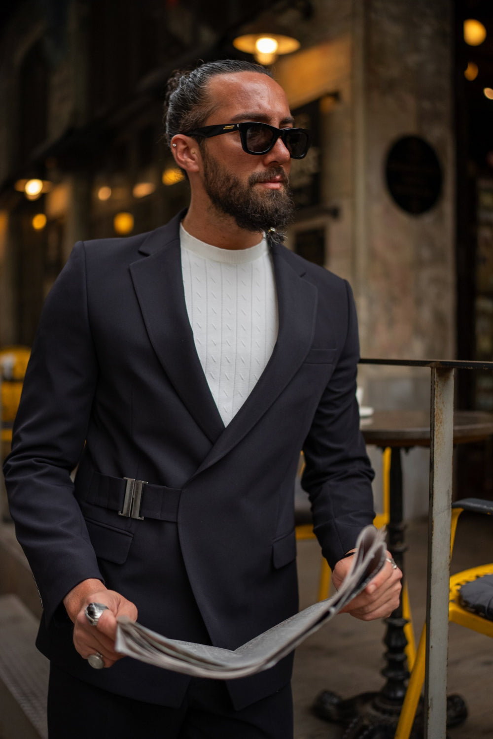 Dark navy asymmetric Mazonni suit with metal buckle detail, styled with a textured white top for a bold modern look
