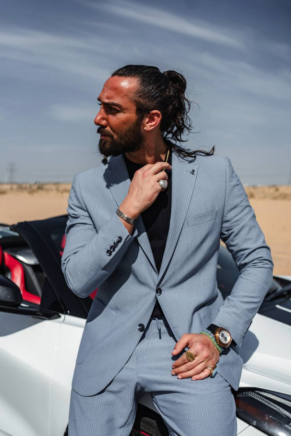 Casual chic light blue suit for men by Mazonni styled with a black tee and gold chain, merging elegance and edge
