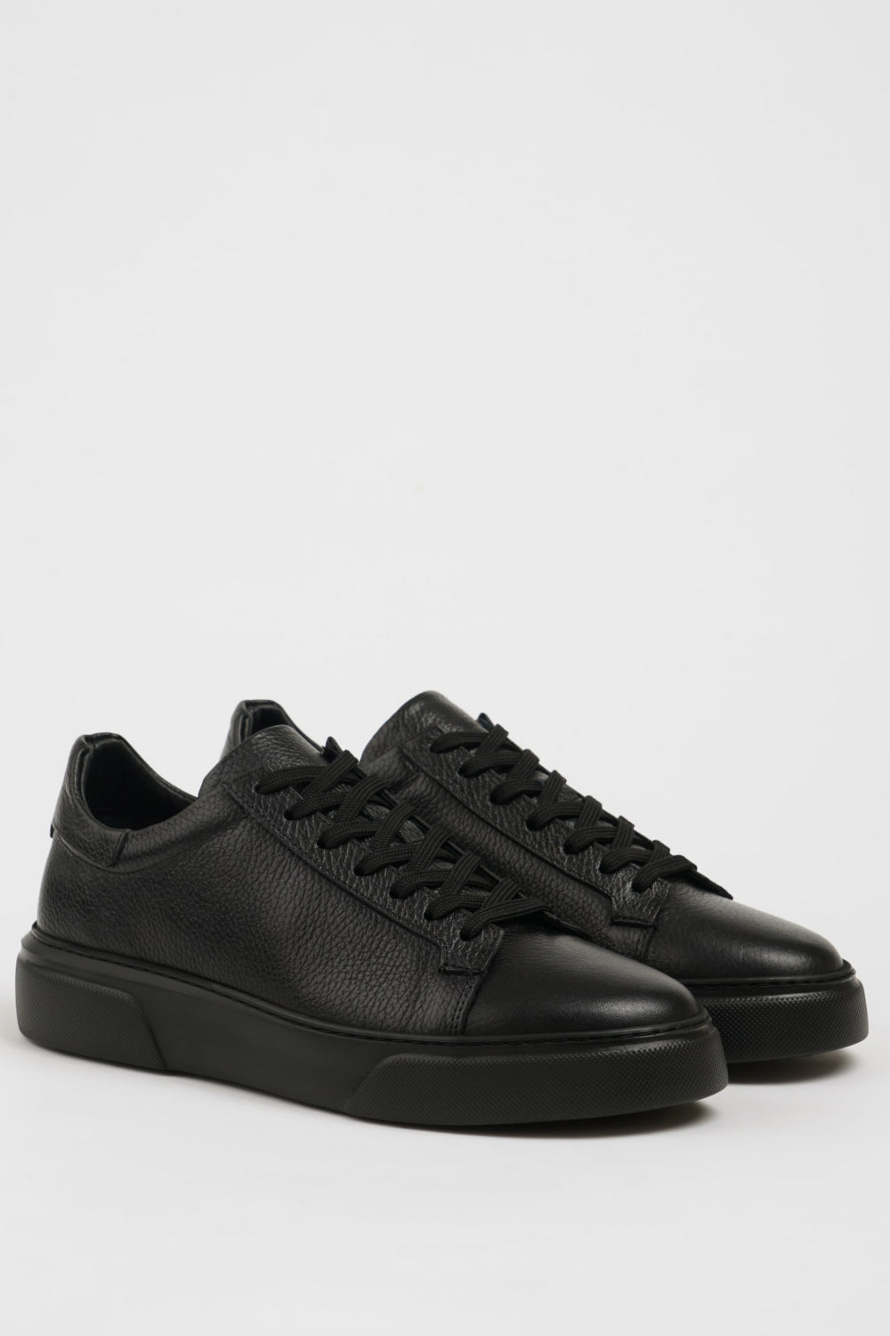Mazonni men’s all-black low-top sneakers featuring smooth finish and rubber sole