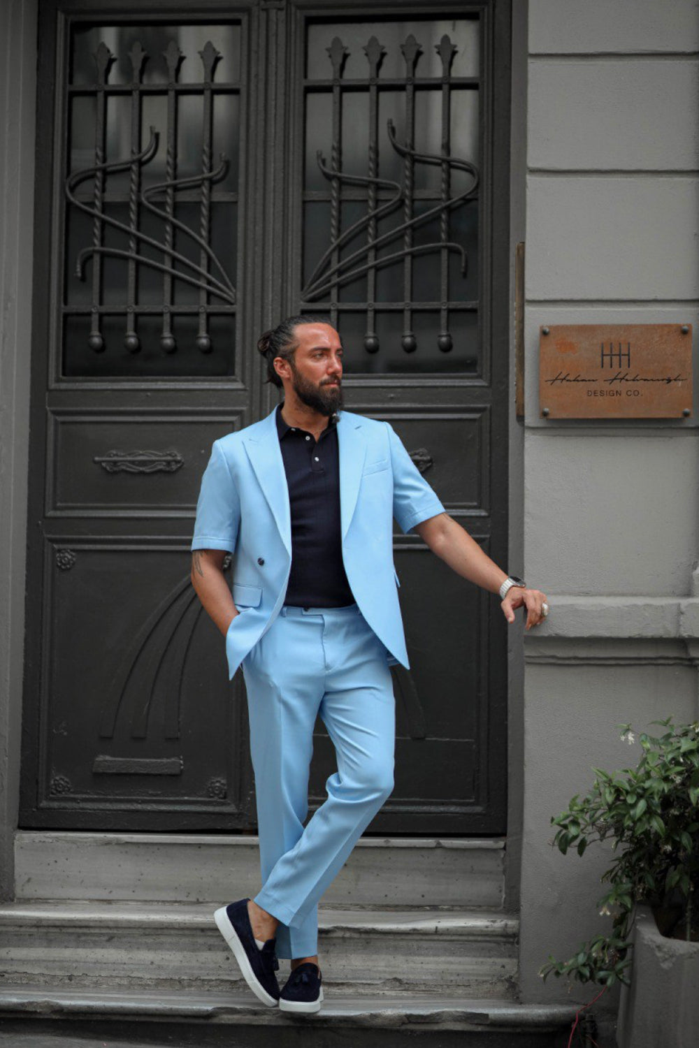 Man wearing light blue short sleeve summer suit with loafers standing confidently