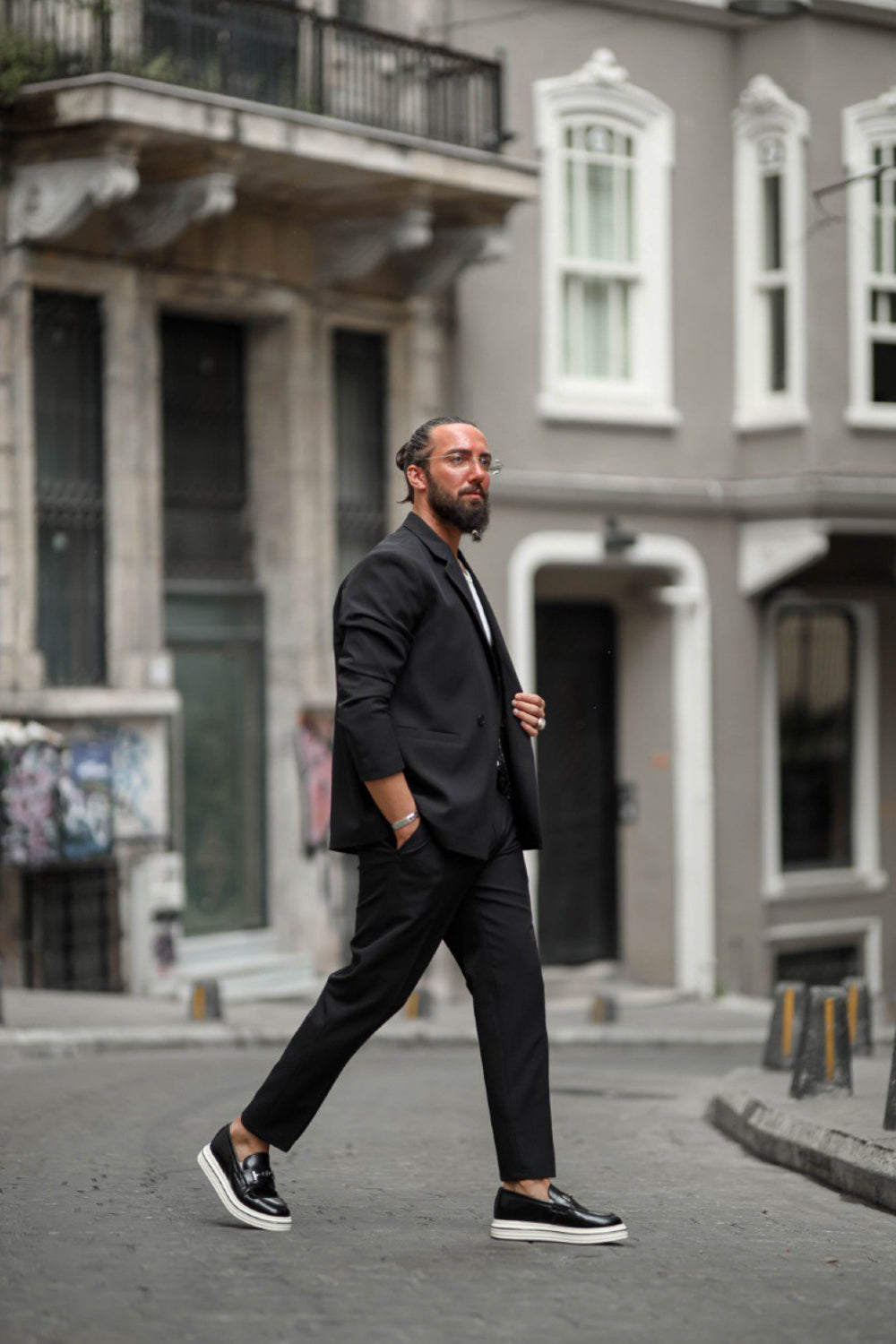Man in relaxed black suit walking confidently in street style fashion