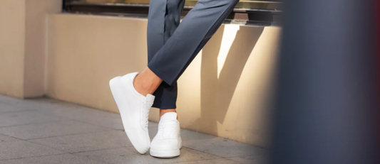 White minimalist sneakers by Mazonni styled with tailored navy trousers – essential casual footwear for men’s wardrobe