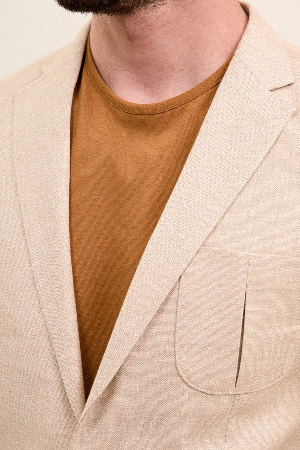 Close-up of Mazonni men’s beige blazer featuring notch lapels and rounded patch pocket – minimal and breathable option for warm seasons