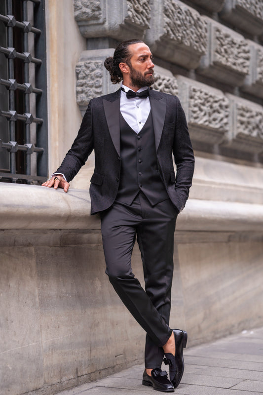 Elegant black tuxedo suit for men by Mazonni with shawl lapel and white dress shirt, perfect for formal evening events