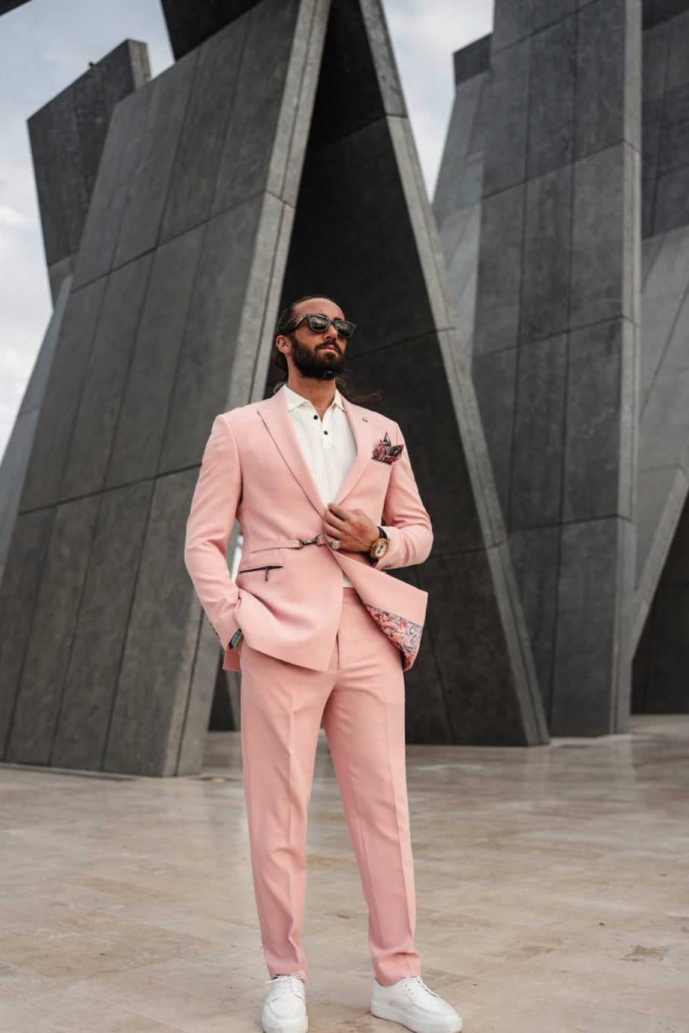 Soft pink men's suit by Mazonni styled in front of contemporary architecture, great for fashion editorials or upscale events