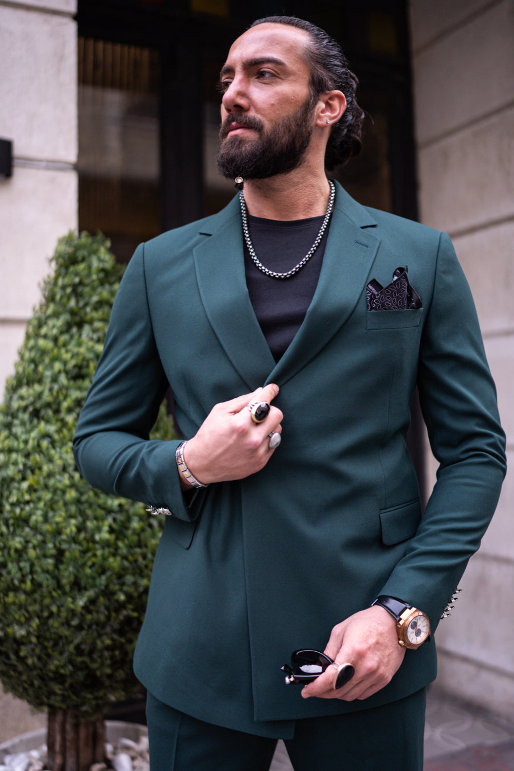 Close-up of Mazonni green suit with double-breasted jacket, gold watch, and layered chain styling