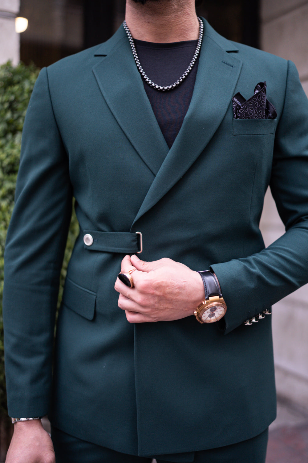 Full-length image of man in dark green Mazonni suit with contemporary accessories and casual footwear