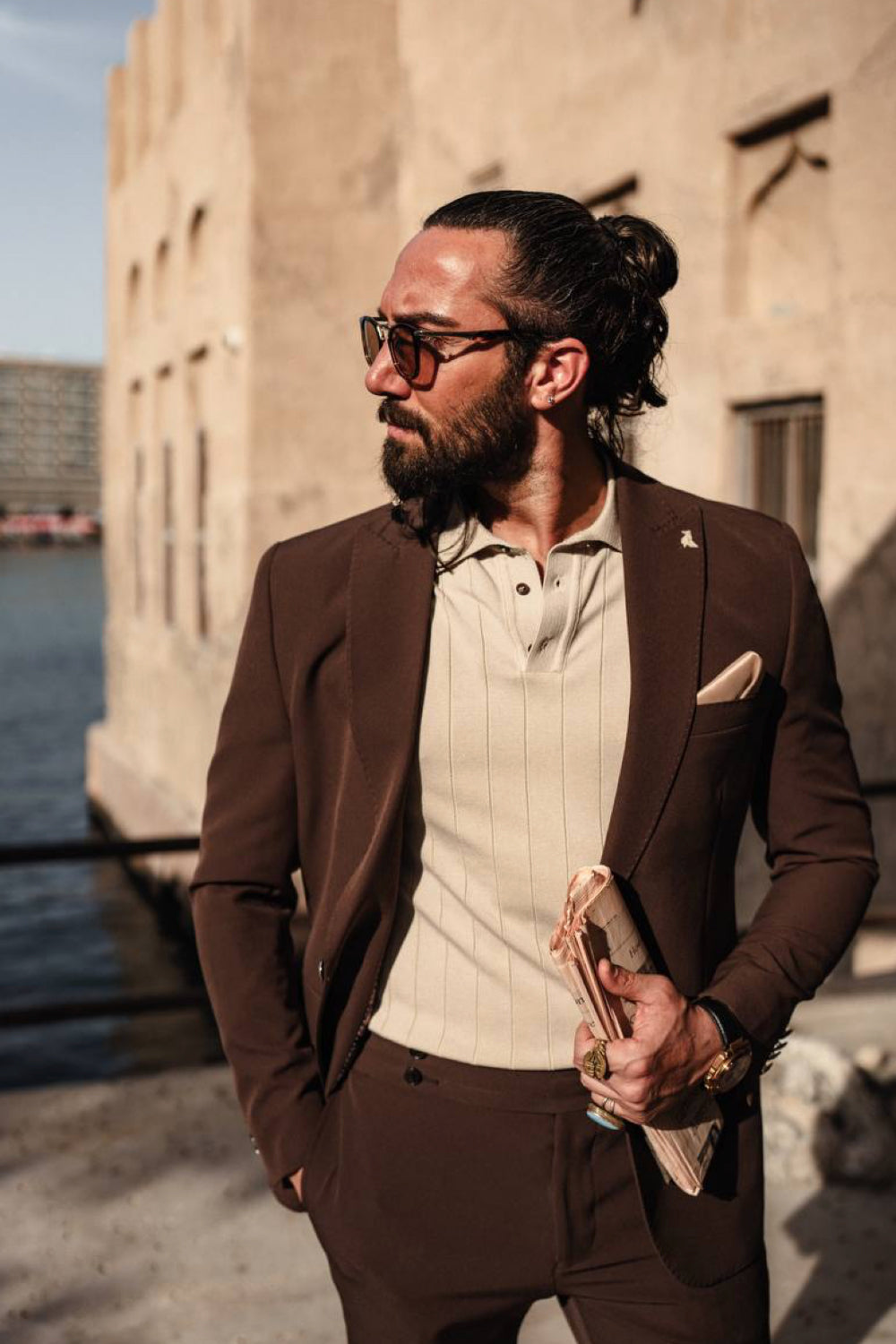Mazonni chocolate brown suit for men styled with a cream polo and pocket square, ideal for outdoor city events or meetings