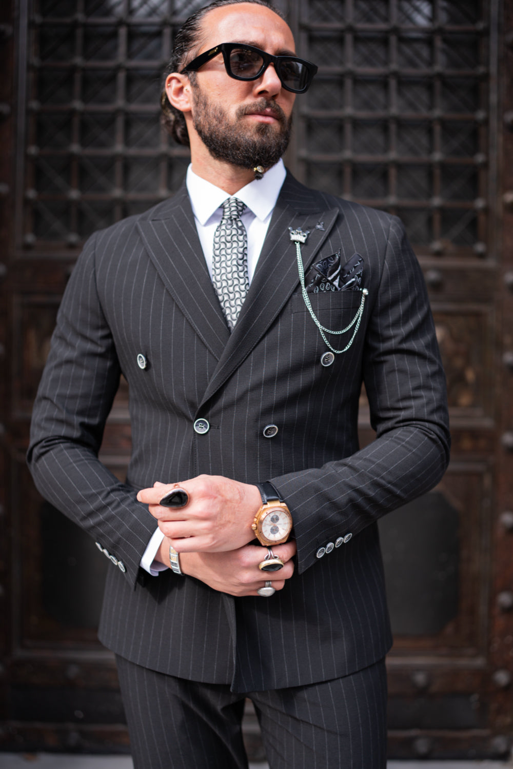 Mazonni black double-breasted striped suit, elegant men’s outfit with silver chain accessory and formal shoes