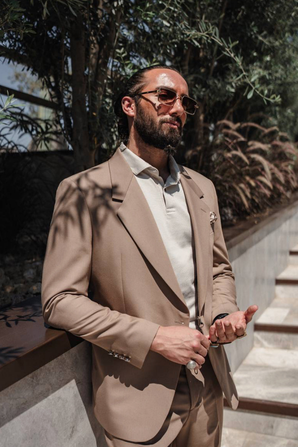 Stylish beige men's suit by Mazonni worn by the water, perfect for warm-weather meetings and upscale resort looks