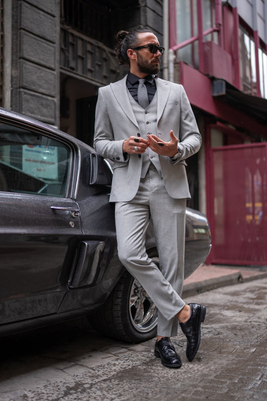 Light grey three-piece suit for men by Mazonni styled with black shirt, perfect for modern weddings or formal events