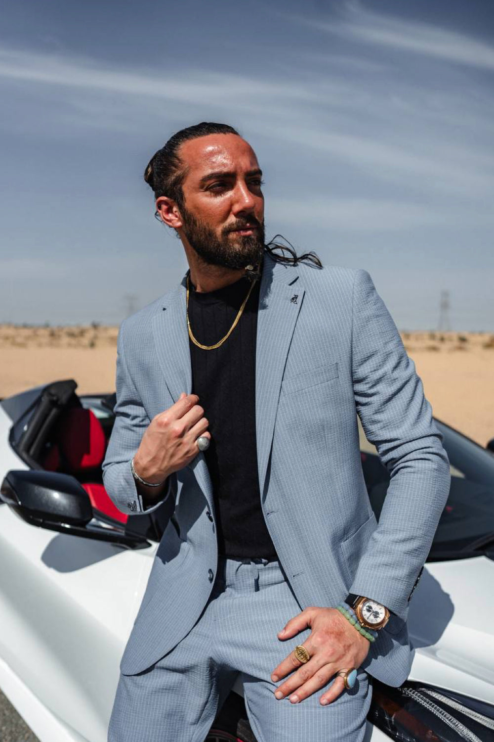 Sleek light blue men's suit by Mazonni shown with a convertible car, ideal for summer formal events with a fashion-forward vibe