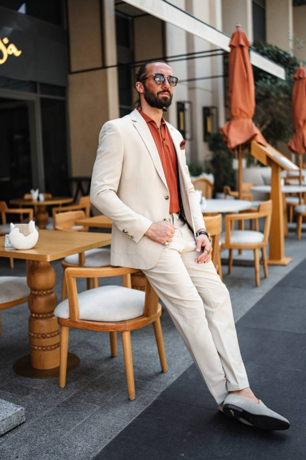 Modern Mazonni men's suit in beige cream, styled for a relaxed city cafe vibe with bold shirt contrast