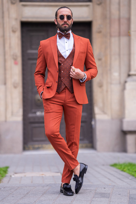 Stylish rust orange three-piece suit for men by Mazonni with patterned vest and bow tie, perfect for weddings and parties