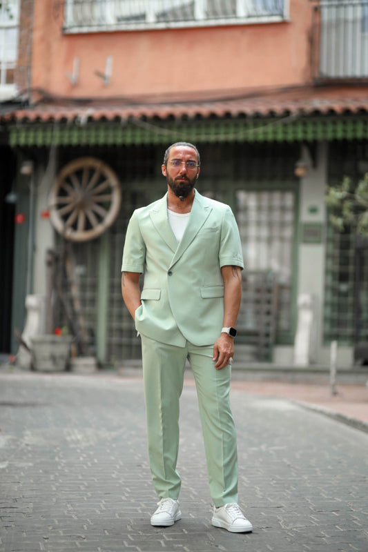 Man in mint green short sleeve suit with white sneakers posing confidently