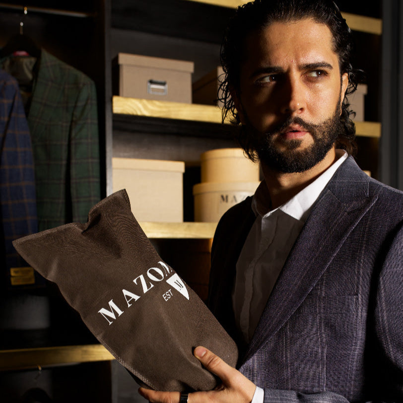 Man in grey MAZONNI suit holding luxury packaging – premium men's fashion and tailored clothing branding