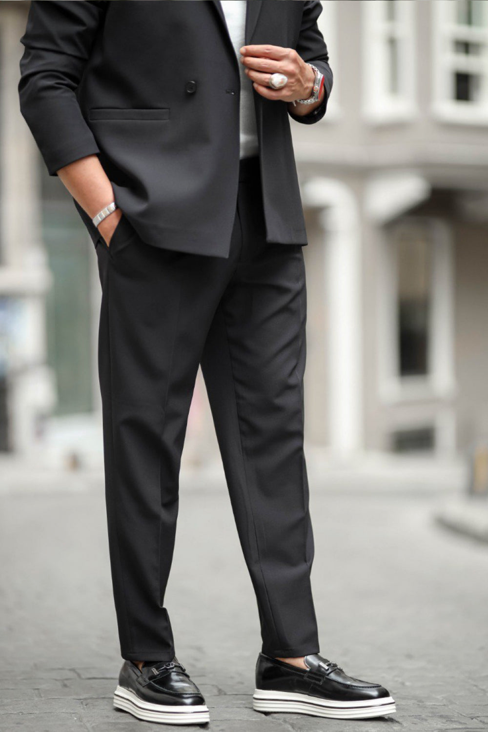 Mazonni black suit worn with white sole loafers in a city fashion setting